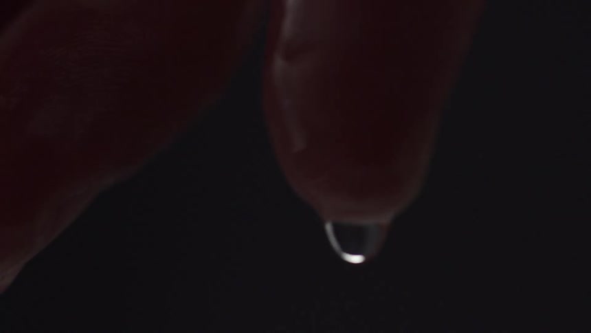 Close up of droplet dropping from finger