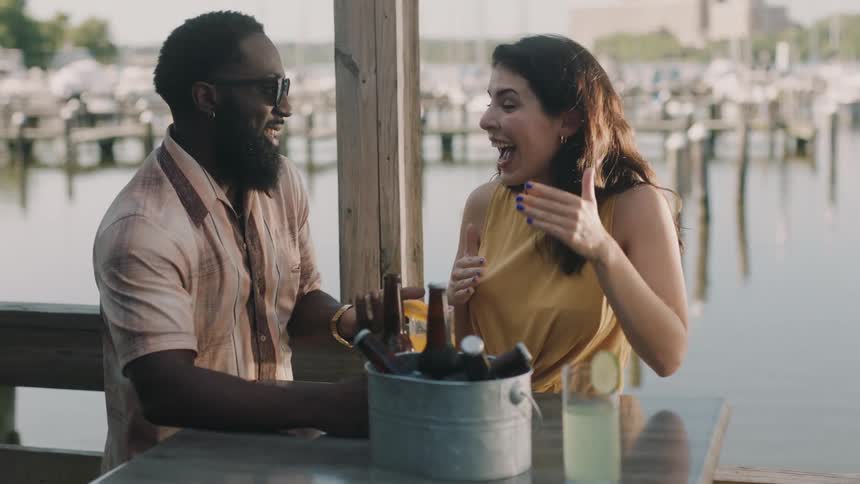 A woman talks with a man at a table next to a marina during the day