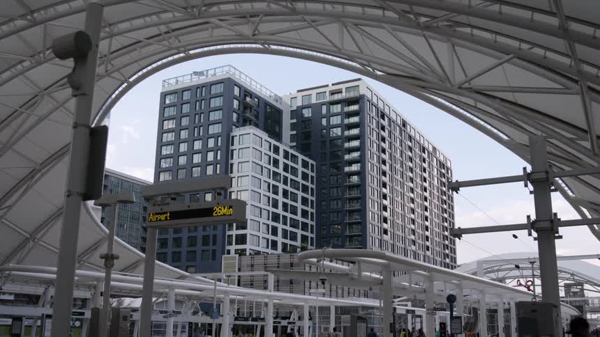 Pedestrians occupy front of airport as person walks across partly open roofed enclosure