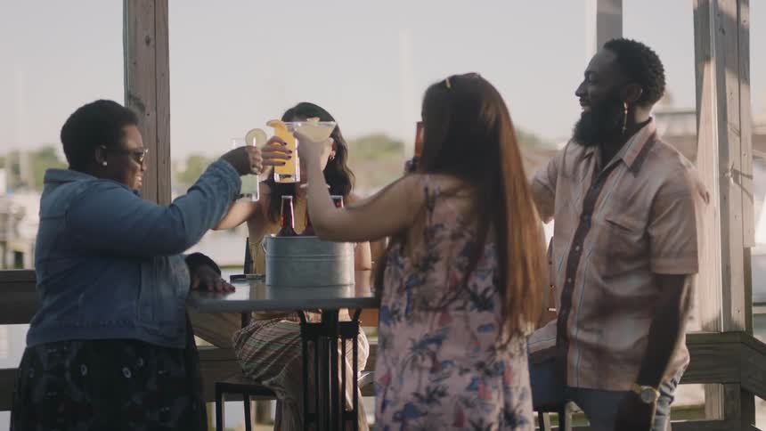 A group of friends are at a restaurant table doing a cheers with drinks