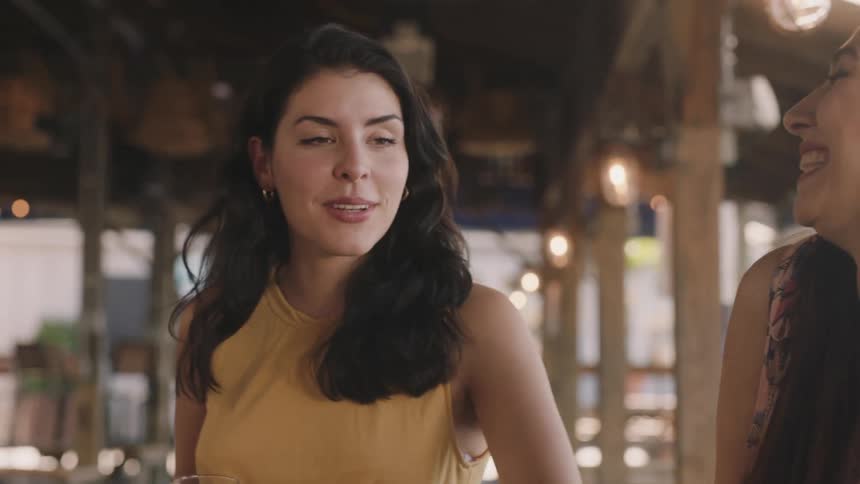 Two women are in a restaurant having drinks and conversation during the day