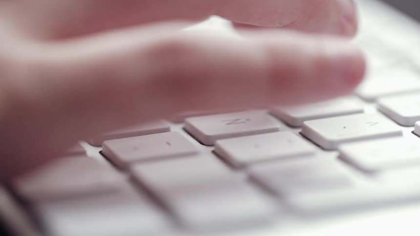 Fingers on a hand press keys on a keyboard