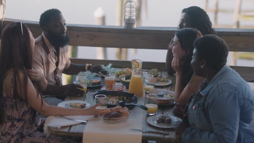 Five people are sitting down having a meal together and talking