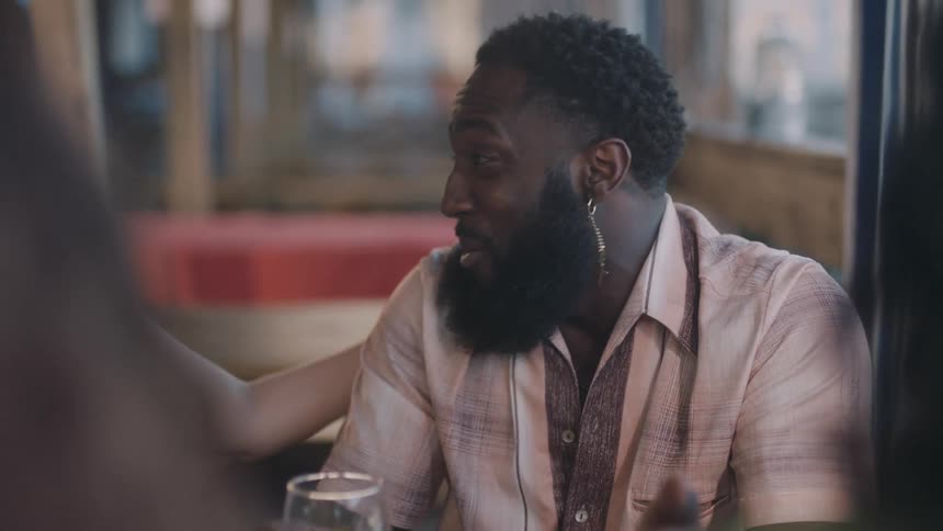 A man and woman sit in a bar and laugh and talk
