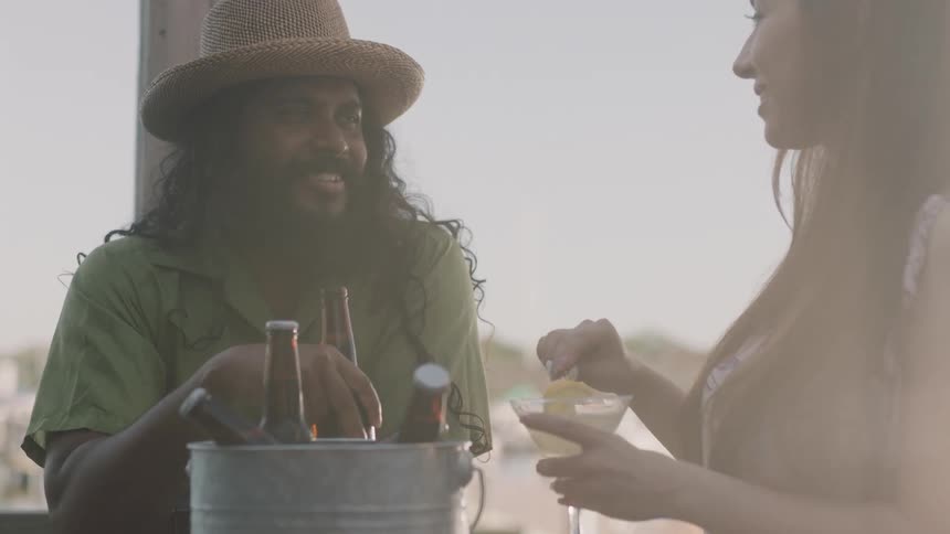 A man and woman are smiling and talking at a table with drinks