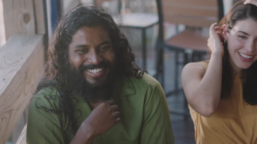 A man and a woman in a room sitting and laughing with chairs in the background