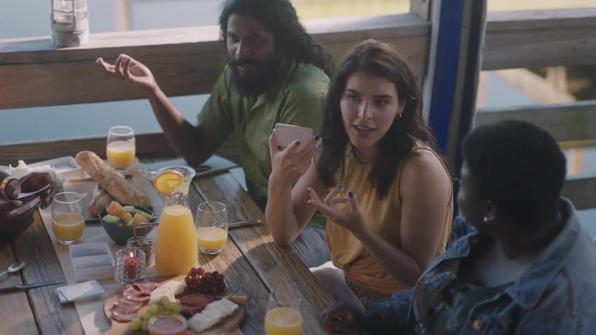 A group of men and women sit at a table at a restaurant and talk and play cards