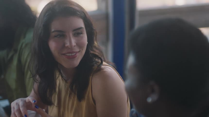 A woman is shuffling cards while smiling and talking to another woman