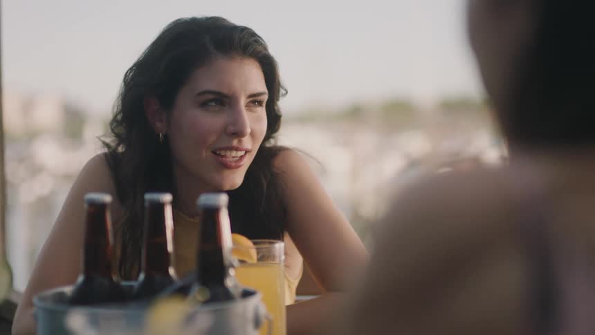 Friends sit at table with beer in ice bucket laughing and talking
