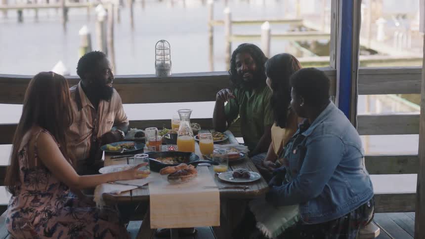 Group of friends talking and laughing while having lunch in a restaurant in the coast