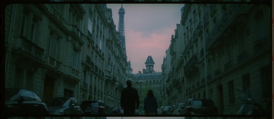 A man and woman walk down a narrow city street