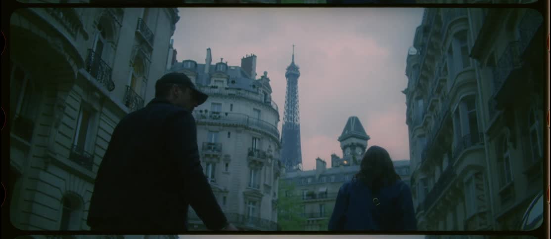 A man puts his arms around a woman as they walk in paris but she pushes him away aggressively