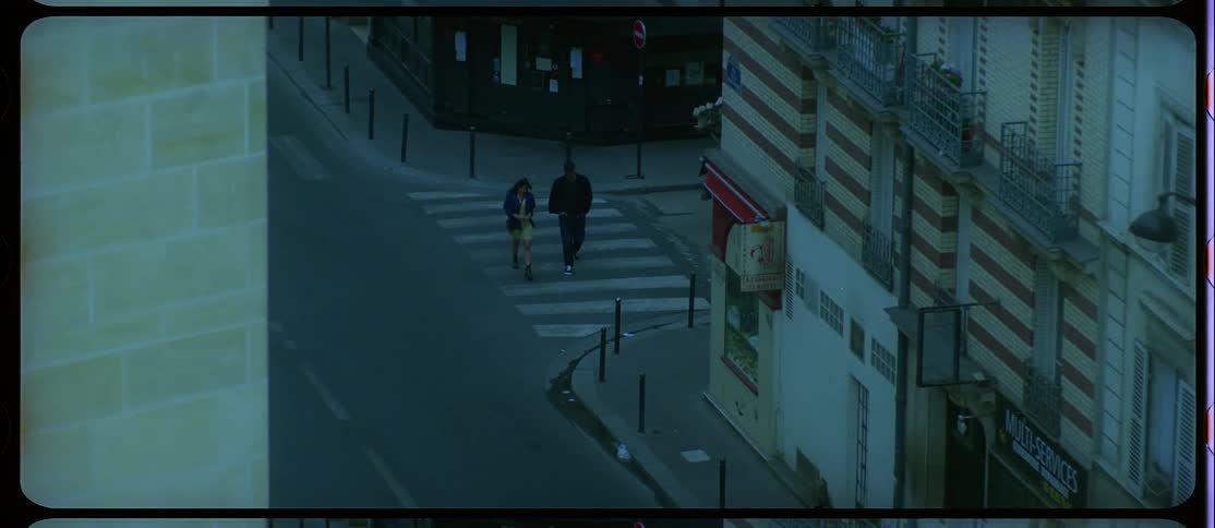 A man and a woman walking on a city street with buildings