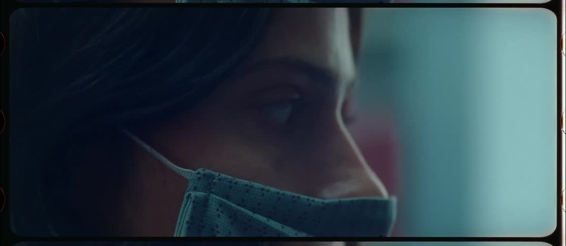 Close up of the face of a woman wearing a cloth face mask caught on vintage film