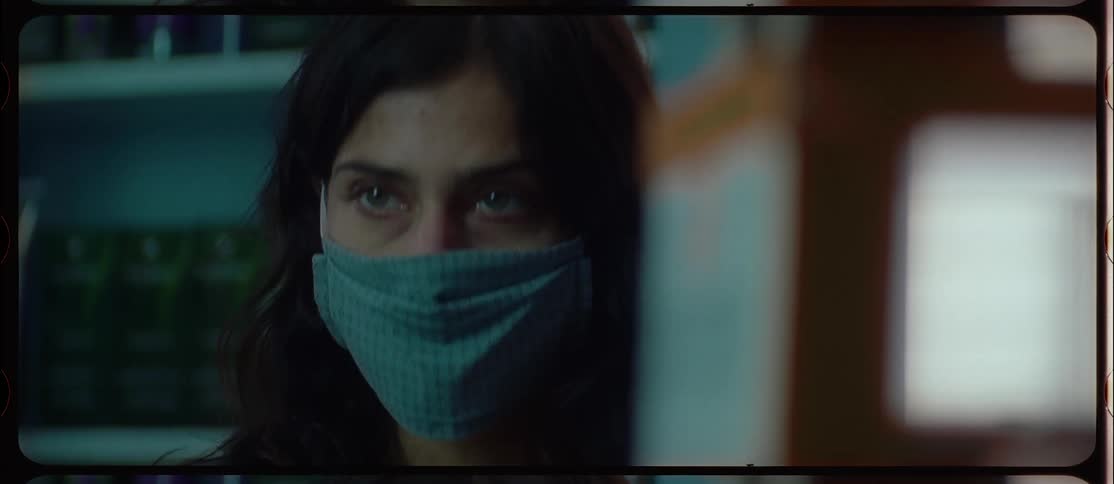 A woman standing in a store wearing a mask looks around at the shelves
