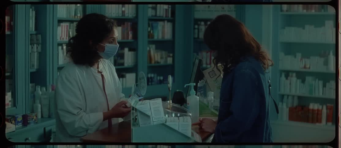 Two women with masks in a room with bottles and shelves in the background