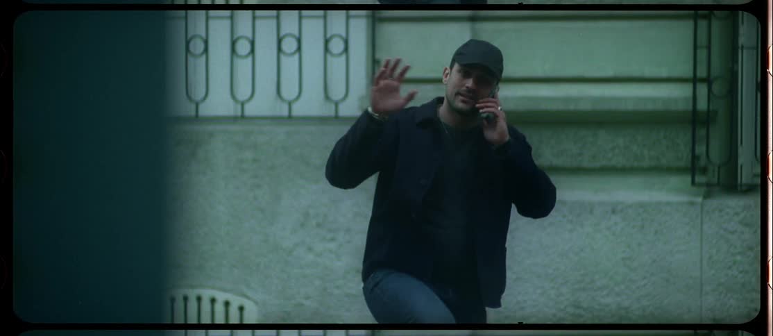 Man talking on the phone moves comedically and waves across the street