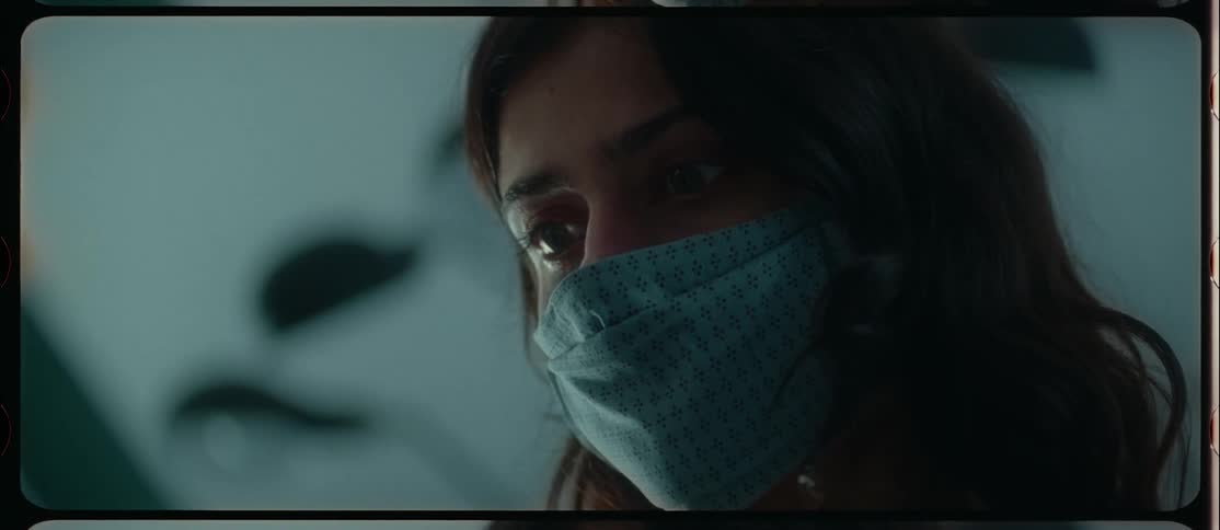 Close up of the face of a woman wearing a cloth face mask caught on vintage film