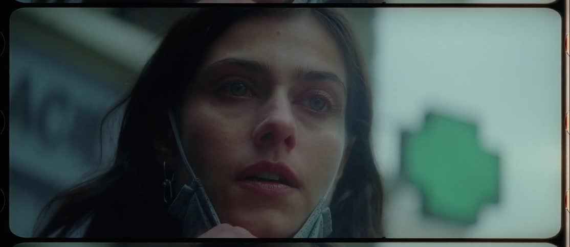 A woman wearing a blue coat and a surgical mask walks out of a door and takes the mask off with a very worried and upset look on her face