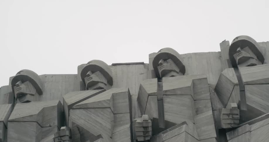 Bird flies from top of angular sculpture of soldiers information