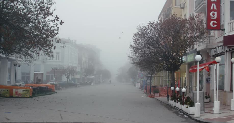 The silhouette of a person walking down a foggy street in a small town