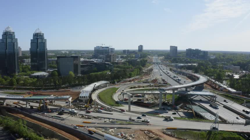 A highway with overpasses and vehicles with trees buildings the sky and clouds in the background