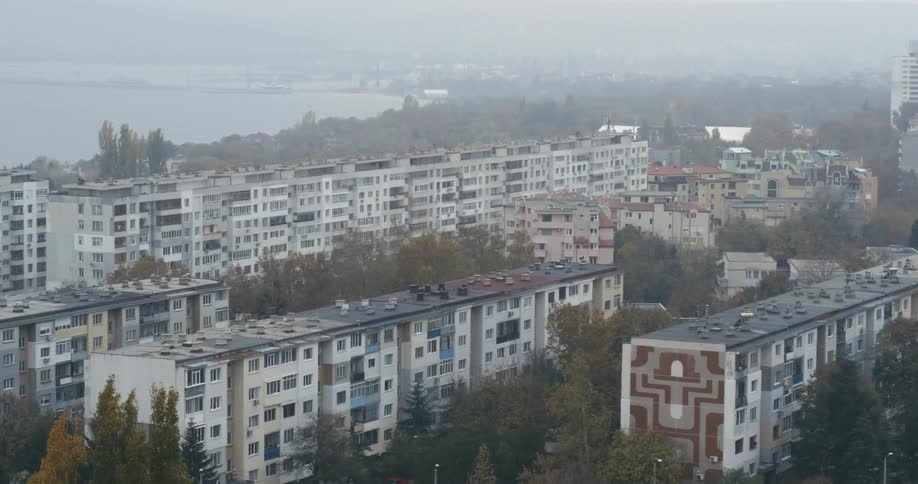 Buildings and trees next to a lake with the sky and clouds in the background