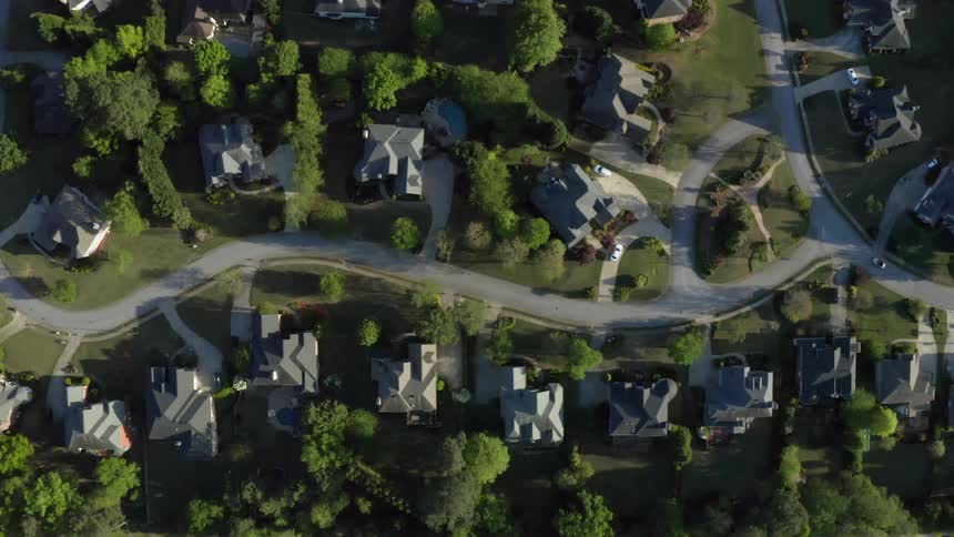 A road winding through houses and trees in a residential area of a town