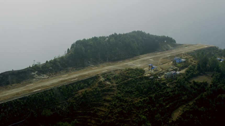 A straight airplane tarmac stretches across the mountain top