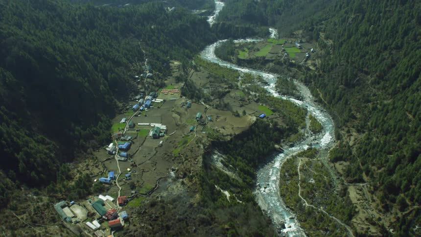 A river is winding its way through a mountain gorge near a village