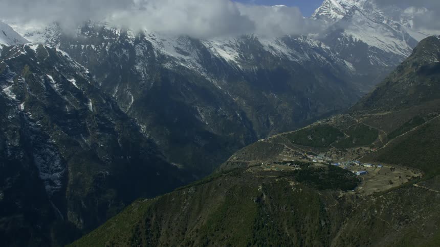 Clouds are drifting over a mountain range and village during the day