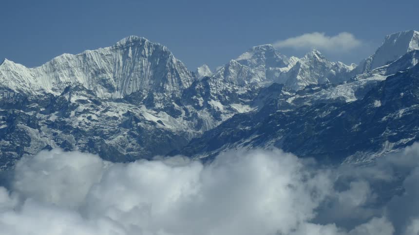 Tall snow covered mountains pierce through the clouds