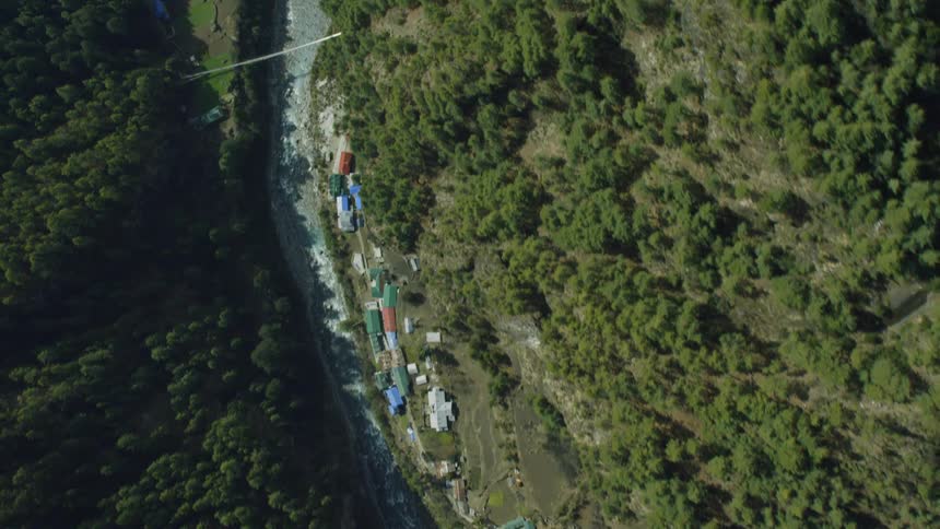 A river is flowing through a mountain gorge near a village during the day