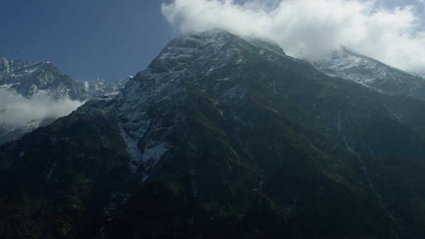 Tall snow covered mountains pierce through the clouds