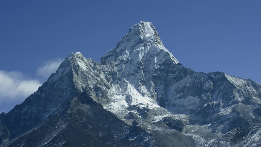 A tall mountain covered in ice pierces through the clouds