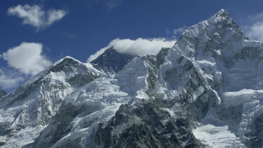 Snow and ice covered mountains pierce through the clouds
