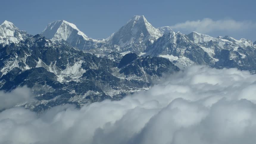 Clouds pass through snowy mountains