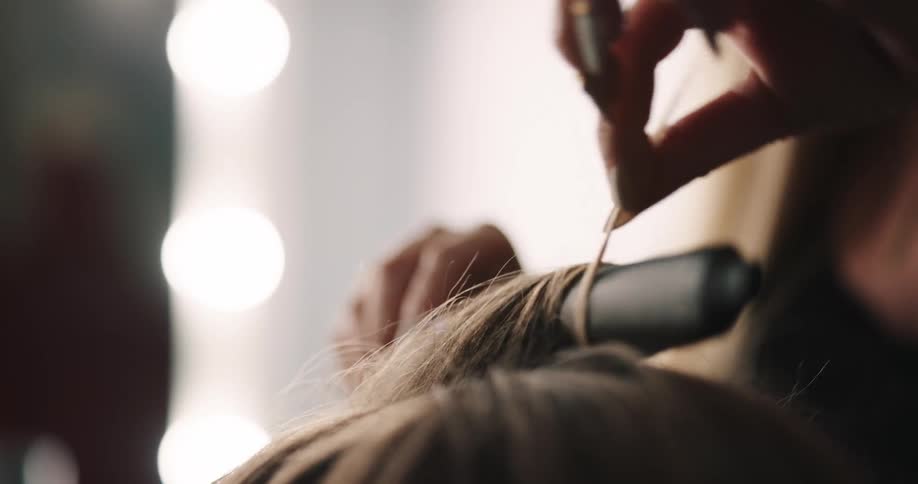 A hair stylist curls a womans hair using hot curlers