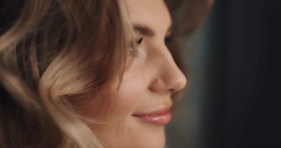 A hairdresser is styling and arranging a womans freshly curled hair