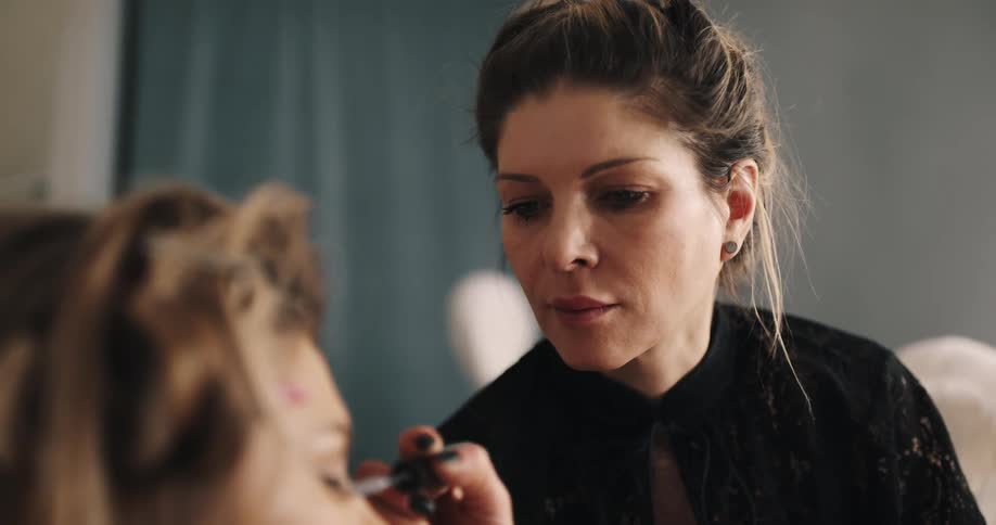 A woman applies makeup to a models face and eyes