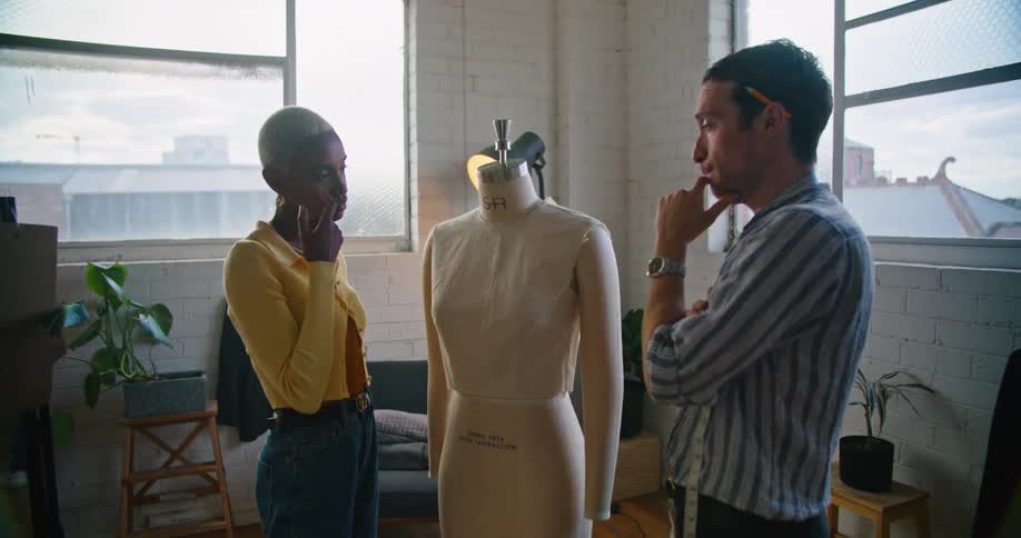 Stylist discussing clothes design on a mannequin with a client