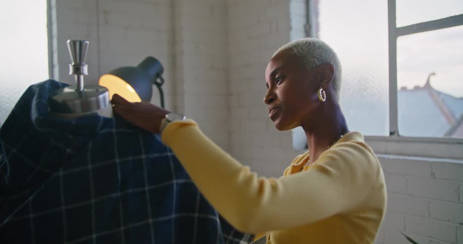 Two clothing designers discuss a plaid fabric on a dress form