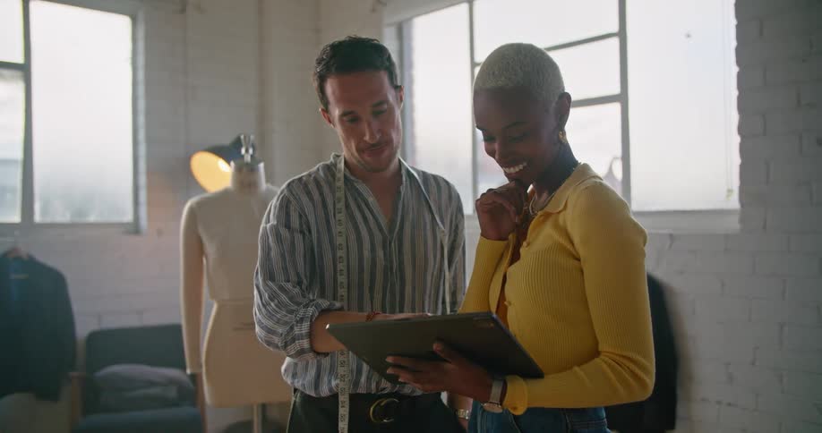 Two suit designers look at a tablet together