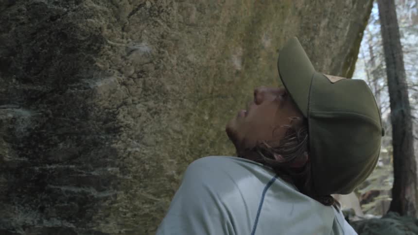 A man looks up at a wall of rock