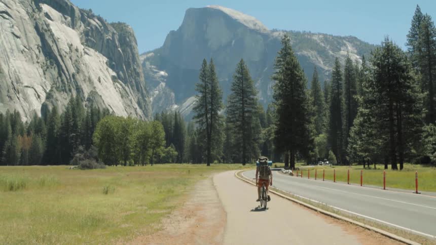 A person rides a bike down a trail near a mountain