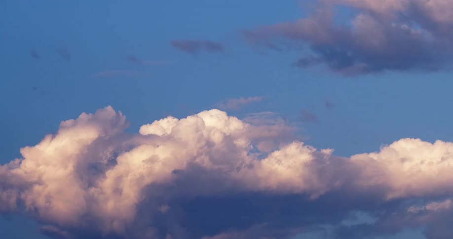 Cumulus clouds move across a blue sky