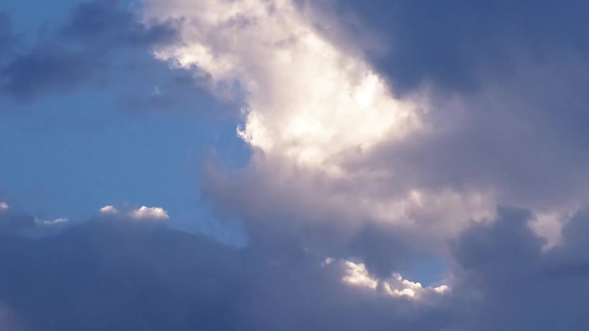 Dark gray clouds flow across sky revealing bright white clouds