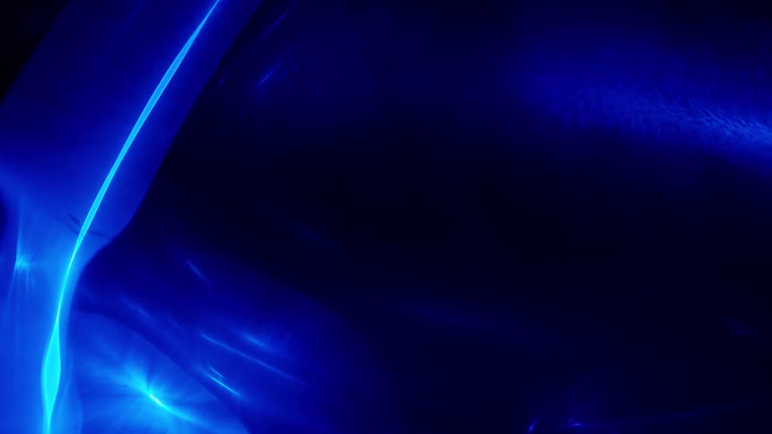 A light shines behind blue waves moving against a black background