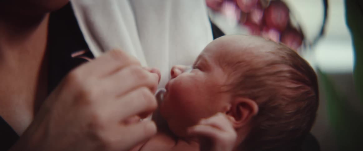 Woman wearing glasses holds baby and cuddles them