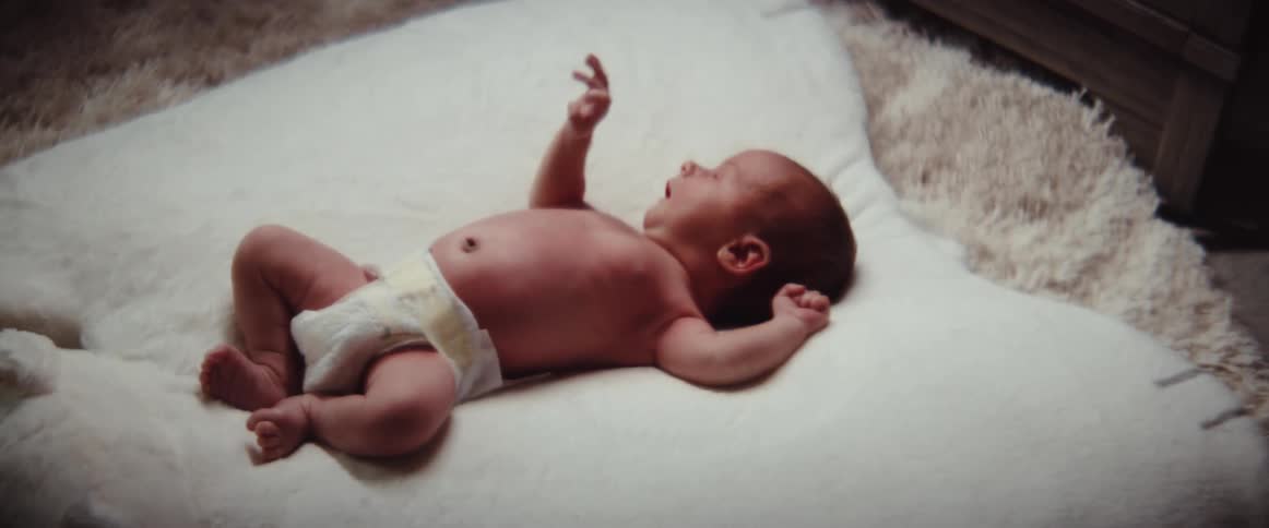 A baby moving around laying in a bed